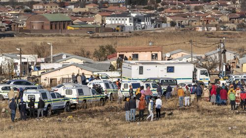 People gather at the scene of an overnight bar shooting in Soweto, South Africa.
