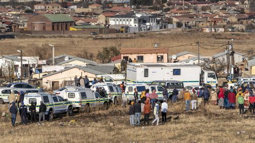 Des gens se rassemblent sur les lieux d'une fusillade nocturne dans un bar à Soweto, en Afrique du Sud.