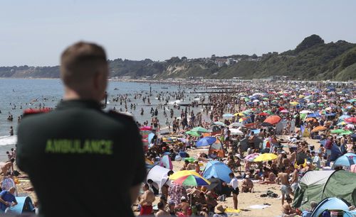 An ambulance officer looks out at people crowded on the beach in Bournemouth, England, on June 25, after coronavirus lockdown restrictions were relaxed.