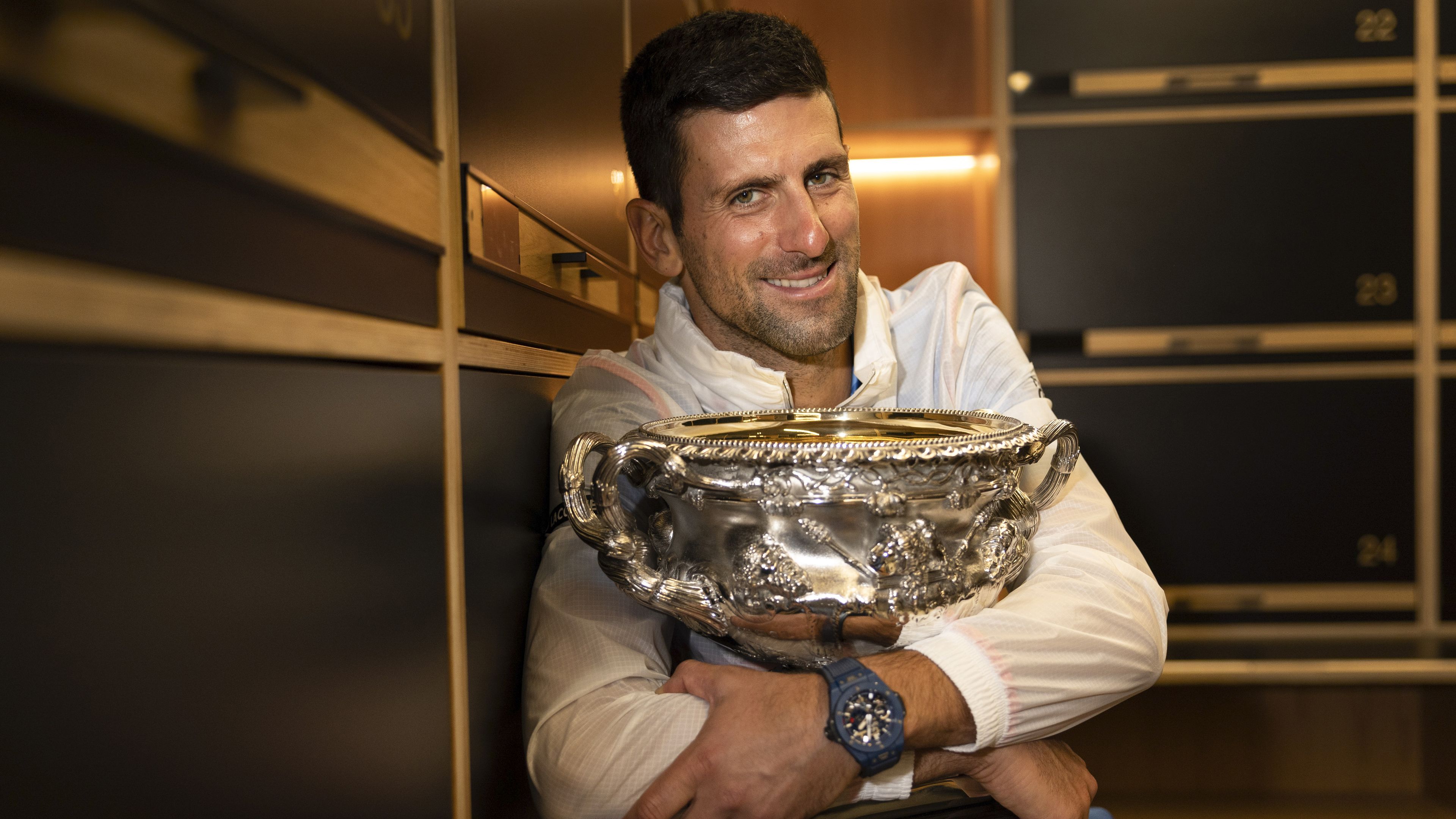 Novak Djokovic of Serbia hugs the Norman Brookes Challenge Cup.