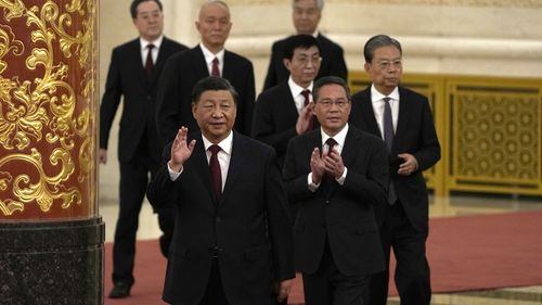 New members of the Politburo Standing Committee, front to back, President Xi Jinping, Li Qiang, Zhao Leji, Wang Huning, Cai Qi, Ding Xuexiang, and Li Xi arrive at the Great Hall of the People in Beijing.