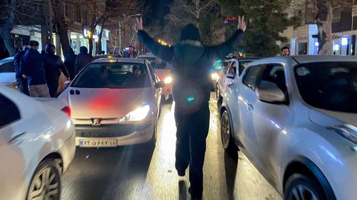 Detriti in fiamme si trovano nel mezzo di una strada durante i disordini a Hamedan, in Iran.