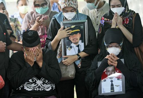 Relatives weep as they pray during the burial of Fadly Satrianto, a victim of the crash of Sriwijaya Air flight SJ-182 in Surabaya, East Java, Indonesia, Friday, Jan. 15, 2021