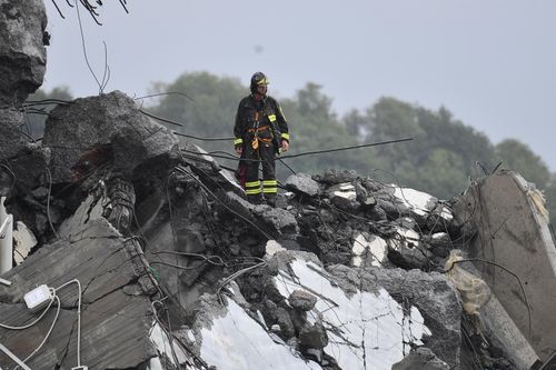 A rescuer looks for bodies in the concrete remnants of the bridge which plunged to the river below. Picture: AP