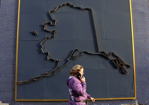 A female connected a compartment telephone walks by a representation of Alaska successful July 2022 successful Anchorage, Alaska.