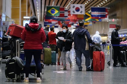 Pasażerowie czekają w kolejce do odprawy na lotnisko Logan we wtorek, 21 grudnia 2021 r. w Bostonie. 