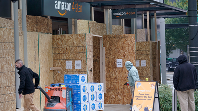 People walk into a business being boarded-up Tuesday, Nov. 3, 2020, in downtown Seattle. (AP Photo/Ted S. Warren)