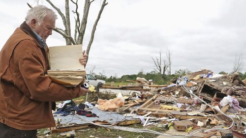 Robert Scott looks through a family Bible that he pulled out of the rubble from his home.