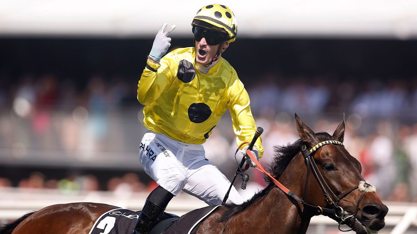 Mark Zahra puts up two fingers to signify his second Melbourne Cup win after crossing the finish line on Without A Fight.