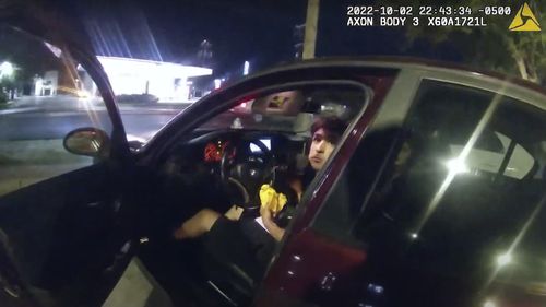 Erik Cantu looks toward San Antonio Police officer James Brennand while holding a hamburger in a fast food restaurant parking lot as the officer opens the car door in San Antonio, Texas. 