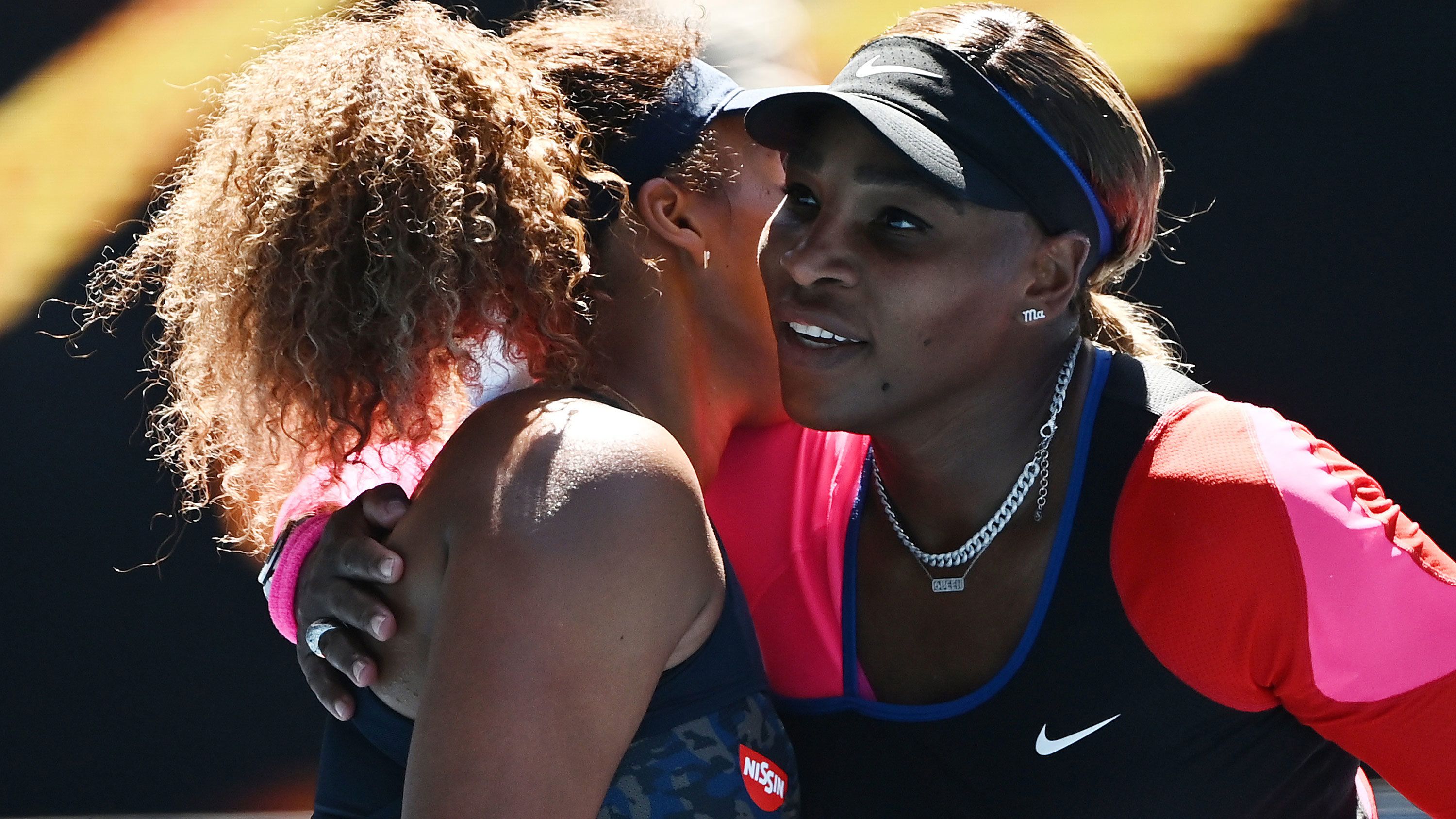 Naomi Osaka is embraced by Serena Williams.