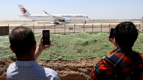 Жители наблюдают, как авиалайнер China Eastern готовится к испытательному полету из нового пекинского международного аэропорта Дасин в понедельник, 13 мая 2019 года.