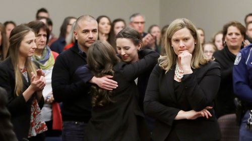 Former gymnast Rachael Denhollander, center, is hugged after giving her victim impact. (AAP)