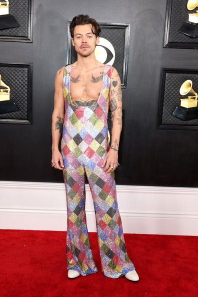 Harry Styles commanded attention on the red carpet in a jaw dropping rainbow, rhinestone embellished jumpsuit.