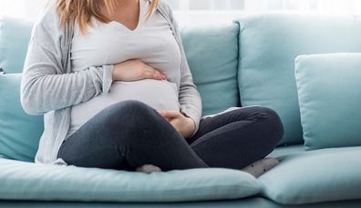 Young pregnant woman suffering from abdominal pain at home