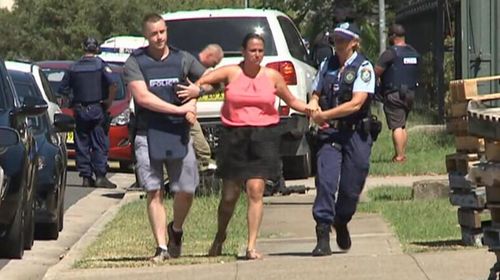 The owner of the sign-making business, Chantelle Tonna, being helped away from the scene by police. (9News)