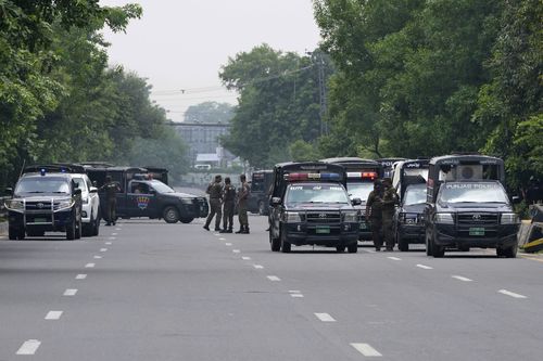Police officers prepare to take position at a road leading to the residence of Pakistan's former Prime Minister Imran Khan, in Lahore, Pakistan, Saturday, Aug. 5, 2023. 
