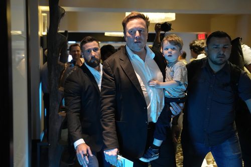Twitter CEO Elon Musk, center, carries his child as he leaves after speaking at the POSSIBLE marketing conference, Tuesday, April 18, 2023, in Miami Beach, Florida
