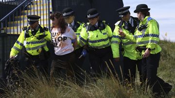 A Just Stop Oil protester is led away by police and security near the 17th hole during the second day of the British Open Golf Championships at the Royal Liverpool Golf Club in Hoylake, England, Friday, July 21, 2023 