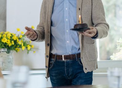 Mature couple celebrating birthday with cake in kitchen at home