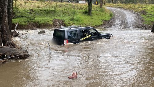 Three people rescued by police officer from car stuck in floodwaters in NSW Hunter region.