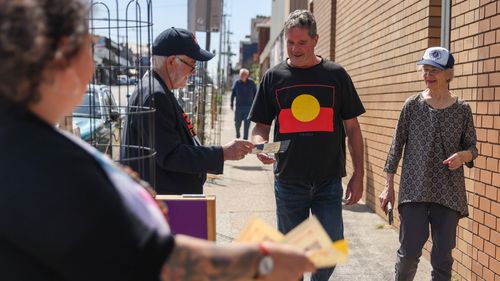 Volunteers hand "how to vote" cards outside a polling booth