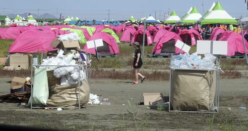 An attendee of the World Scout Jamboree walks by garbage and items for recycling at a scout camping site in Buan, South Korea, Friday, Aug. 4, 2023.  