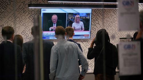 Staff in the green room watch a television screen showing presenters Andrew Neil and Michelle Dewberry broadcast from a studio, during the launch event for new TV channel GB News.