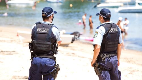 Police at a beach in northern Sydney ensure crowd limits fall within guidelines for coronavirus restrictions.