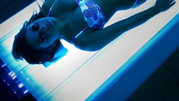 A woman uses a tanning bed.