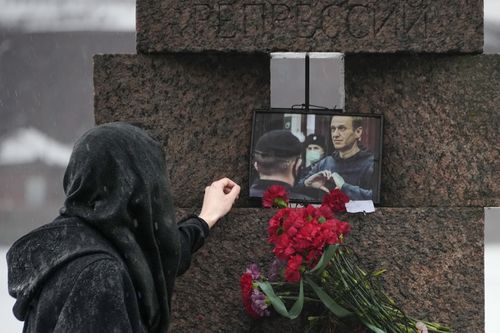 A woman touches a photo of Alexei Navalny after laying flowers paying the last respect to him at the Memorial to Victims of Political Repression in St. Petersburg, Russia on Saturday, Feb. 17, 2024