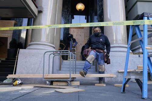 A work crew applies wooden boards to the exterior of The Westin Saint Francis San Francisco on Union Square hotel in San Francisco, Monday, Nov. 2, 2020, ahead of Election Day. (AP Photo/Jeff Chiu)