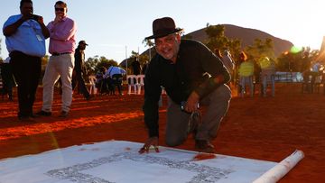 Noel Pearson signs the canvas where the Uluru Statement from the Heart will be painted on, in this photo from 2017.