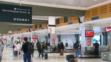 Returning travellers mull around a Qantas baggage claim.