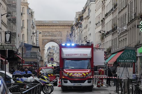 Une ambulance des pompiers est vue derrière une bande de police où une fusillade a eu lieu à Paris, le vendredi 23 décembre 2022. 