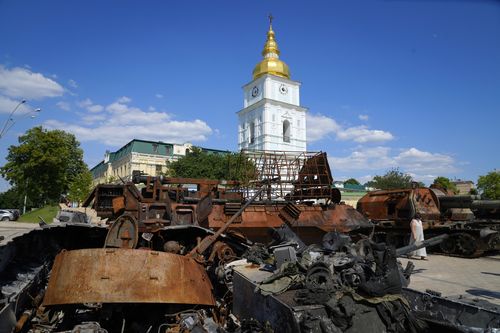 Una mujer mira un tanque ruso destruido instalado como símbolo de guerra en el centro de Kyiv, Ucrania, el martes 7 de junio de 2022. La Catedral de San Miguel está al fondo.