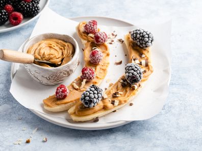 Banana with peanut butter spread on top and covered in frozen berries.