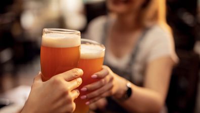 Two people toasting beer in a bar