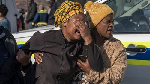 Une femme pleure sur les lieux d'une fusillade nocturne dans un bar à Soweto, en Afrique du Sud,