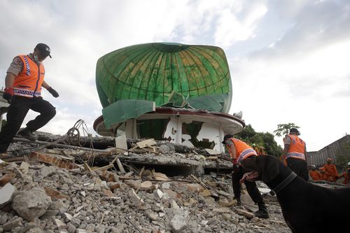 Yesterday, rescuer officers worked to clear the rubble from a local mosque that was pancaked in the earthquake. Picture: AP.