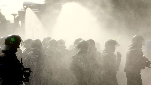 A police water cannon is accidentally pointed at officers in riot gear during a demonstration against the G20 summit in Hamburg, Germany. (AFP)