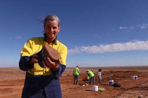 Robyn Mackenzie, director and paleontologist at the Eromanga Natural History Museum, holds up a dinosaur bone.