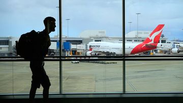 A passenger walks past a Qantas jet at the International terminal at Sydney Airport