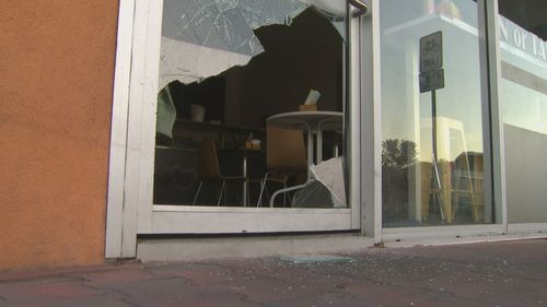 The smashed in door of one of the businesses.