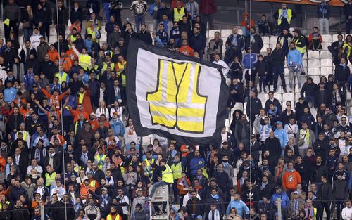 Marseille fans at a football match yesterday wave a banner showing a hi-vis vest in support of the rioters.