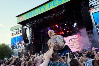 A person in a wheelchair crowd surfs at Ability Fest 2021.