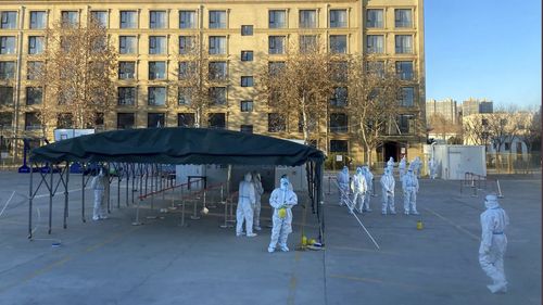 Workers in protective clothing prepare to receive passengers from a flight coming from outside China to be quarantined due to COVID-19 surges following the easing of pandemic-related restrictions, at a resort on the outskirts of Beijing, China, Thursday, Dec. 22, 2022. (AP Photo/Ken Moritsugu)