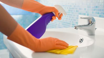 A woman cleans the bathroom sink.