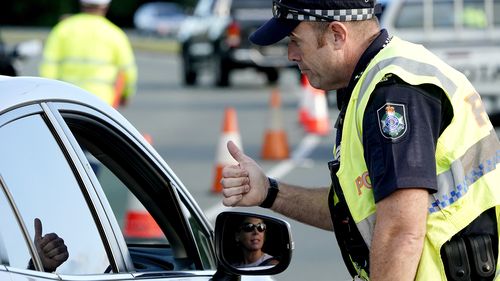 A motorist  is given the thumbs up by a police officer after being stopped at a checkpoint on the Gold Coast Highway at Coolangatta on the Queensland/NSW border,