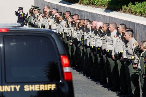 Local police saluted as Ron Helus' body was transferred to a coroner's office.